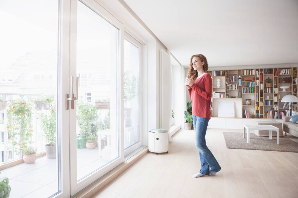 Mujer en casa mirando por la ventana - Puertas y ventanas de pvc Termprotect
