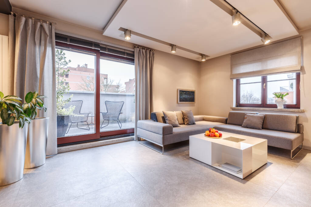 Salón moderno con ventanal corredero de PVC y luz natural, diseño minimalista GEALAN-LINEAR®.