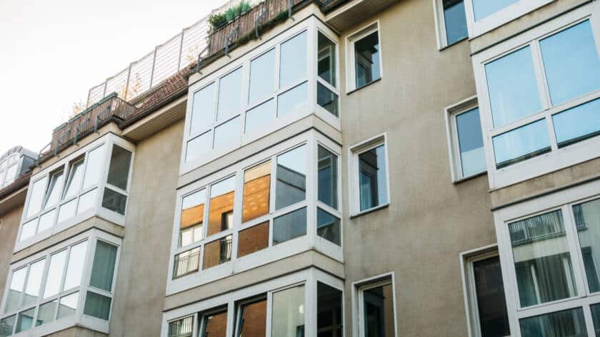 Fachada de edificio moderno en Madrid con grandes ventanas PVC y balcones acristalados para el aislamiento térmico.