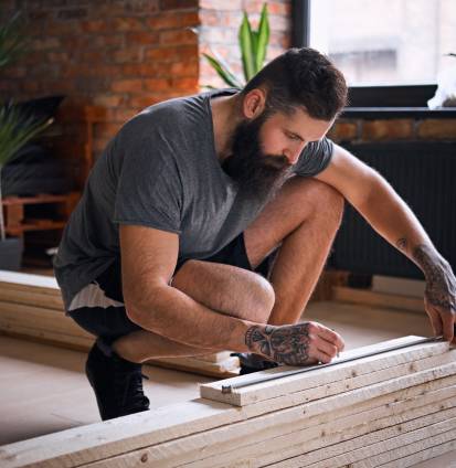 Carpintero midiendo tablas en una habitación con interior tipo loft - puertas y ventanas de pvc Termprotect